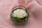 A round bowl containing a preserved peach rose set on preserved green hydrangea.