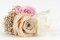 A boutonniere for a special occasion in pale pink and beige tones, made with preserved flowers and foliage.